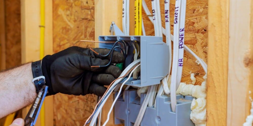 Electrician installing a power outlet in a new home.